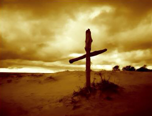 [Photo of a cross in the desert during a sunrise]