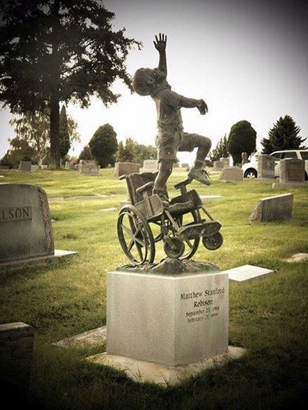 [Photo of a tombstone depicting a boy leaping from his wheel chair]
