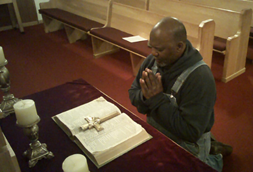 Photo of man kneeling at the altar of a church
