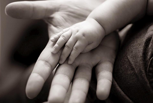 Photo of a small child's hand inside an adult's hand