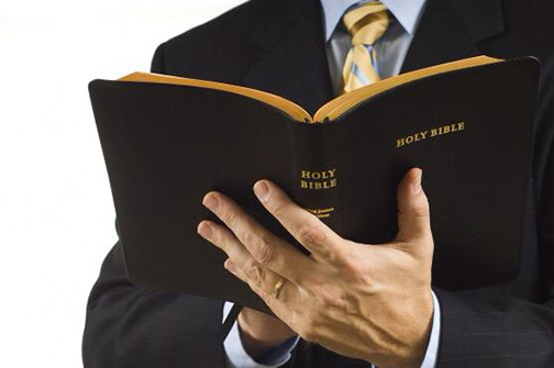 [Photo of a man hholding an open Bible]