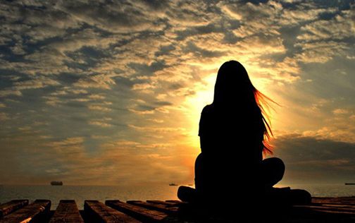 [Photo of a woman praying at sunrise]