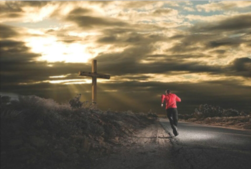 Photo of a runner running toward a cross at daybreak