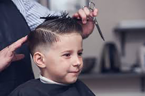 [Photo of a young boy geting a haircut]